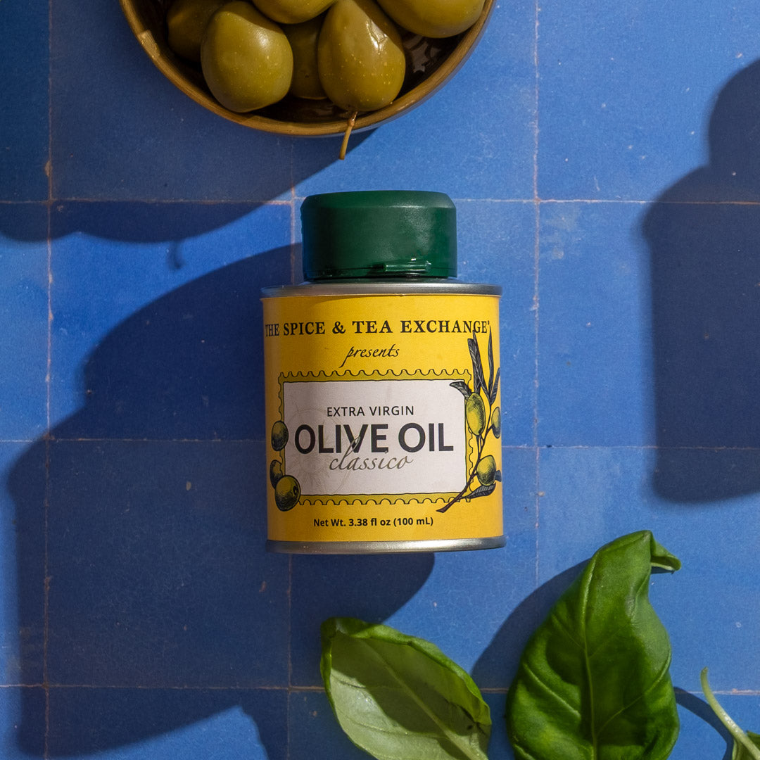 Can of Classic Extra Virgin Olive Oil - Mini with a yellow label on a blue tiled background